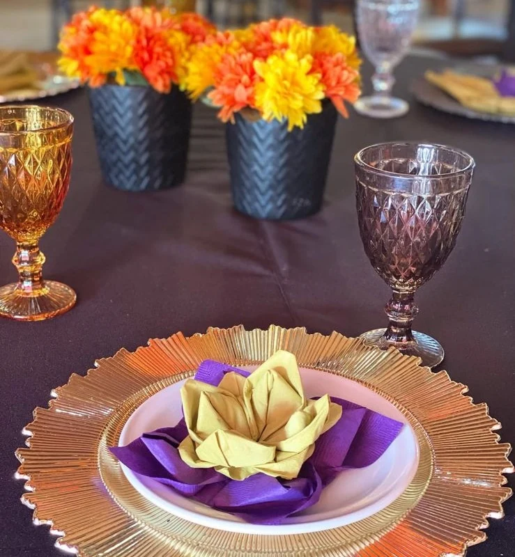 Mesa puesta en Al Son de México, con platos de barro, copas y flores de temporada